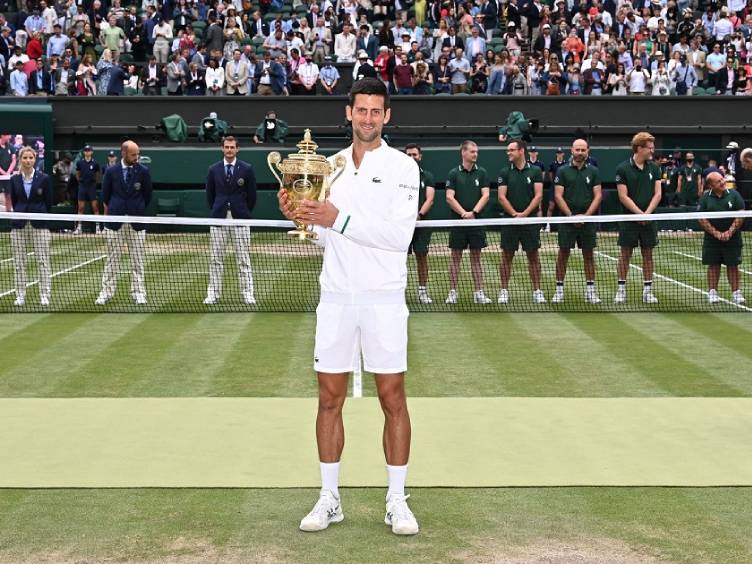 Novak Djokovic com o troféu de campeão de Wimbledon 2021 na grama sagrada londrina