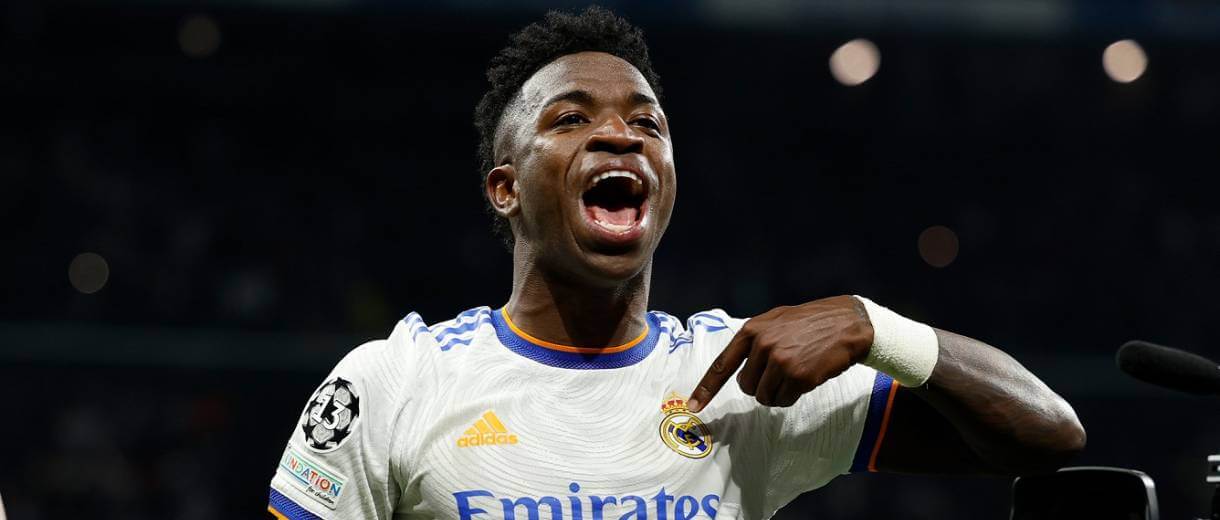 em destaque vinicius junior apontando para escudo do real madrid na camisa